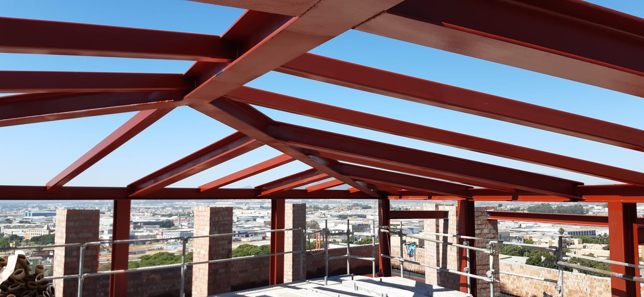 Estructura de acero con vigas pintadas en rojo, diseñada para soportar cubiertas metálicas.
