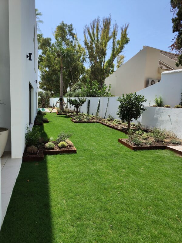 Borduras de acero corten delimitando los parterres, aportando un acabado elegante y duradero..