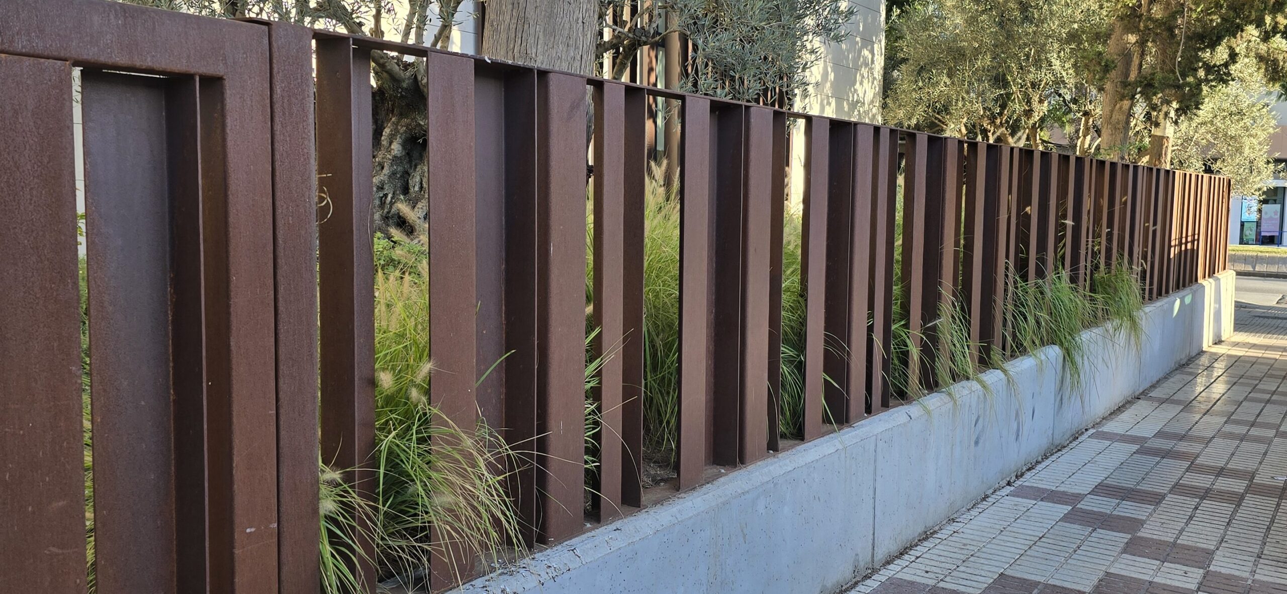Valla fabricada en acero corten instalada en una zona urbana, ideal para delimitar espacios con estilo y durabilidad.